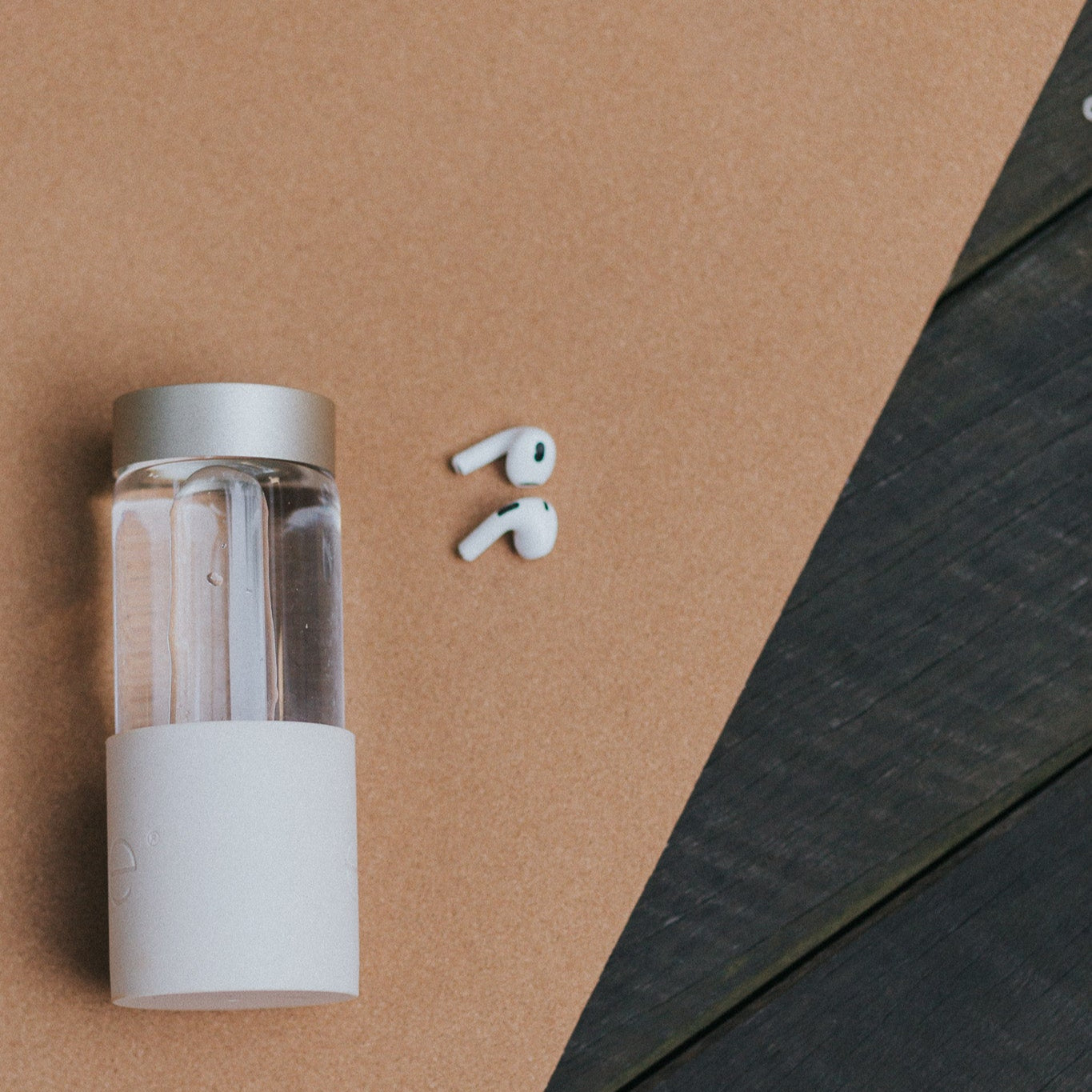 clear glass water bottle with earphones on a yoga mat on a wooden floor