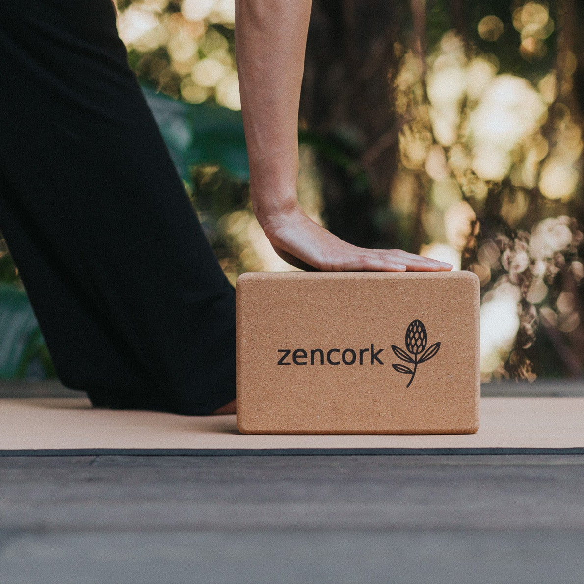 Person using a cork yoga block with 'zencork' branding outdoors.