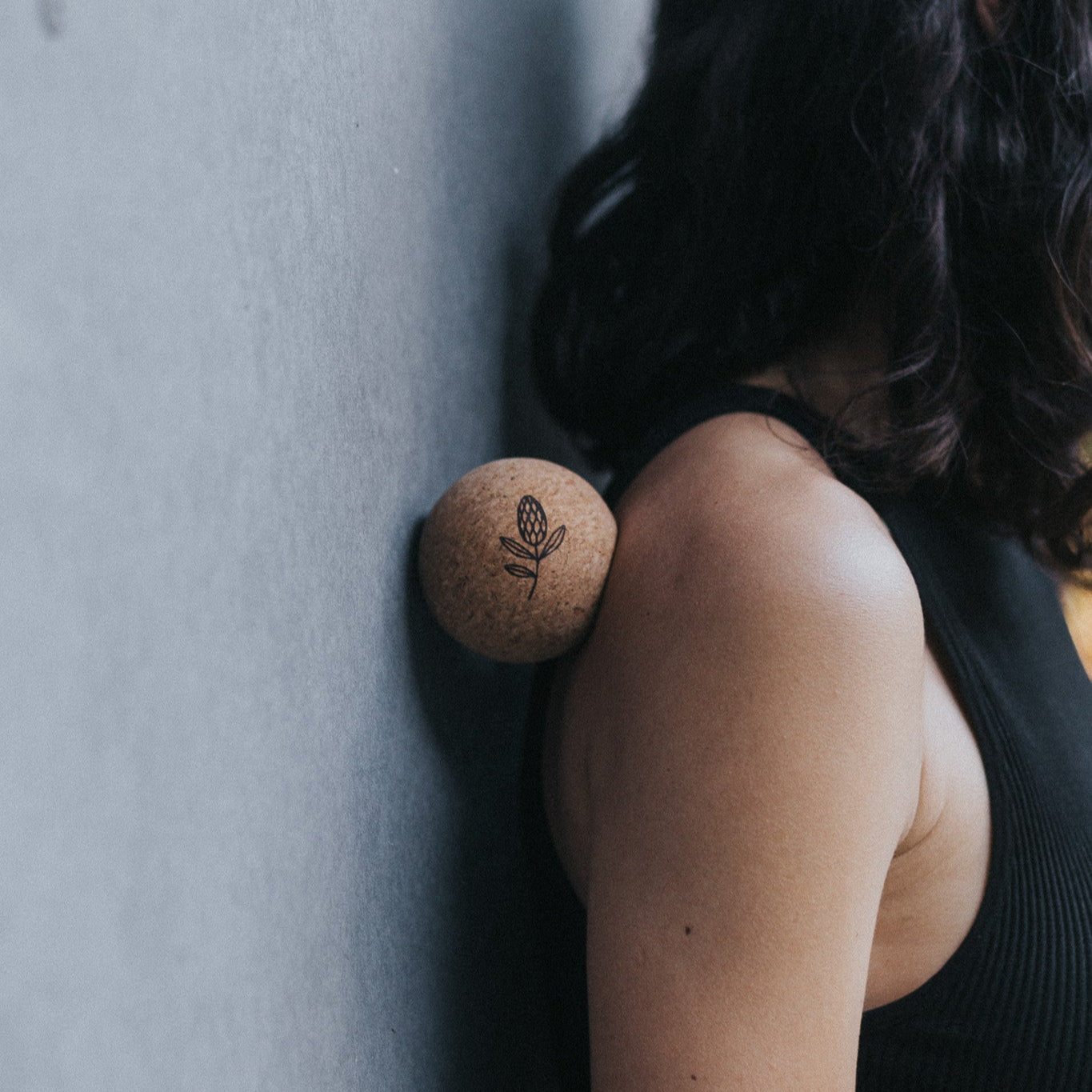 Person holding a cork yoga ball against a grey wall