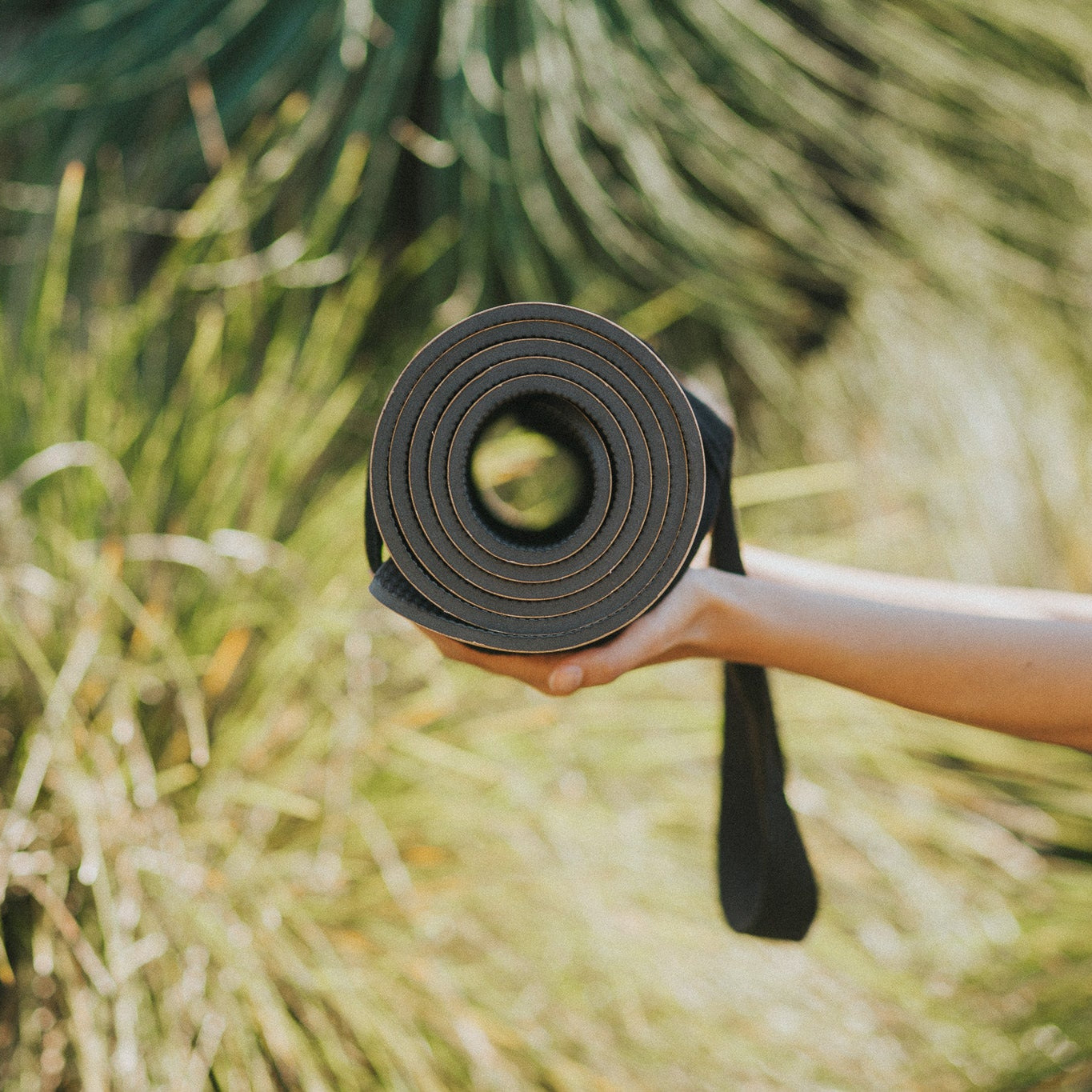 Person holding a yoga mat with a natural background