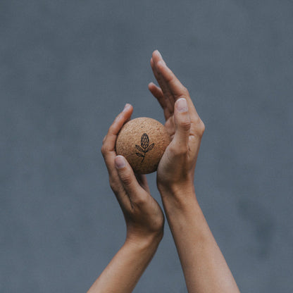 Two hands holding a cork massage ball