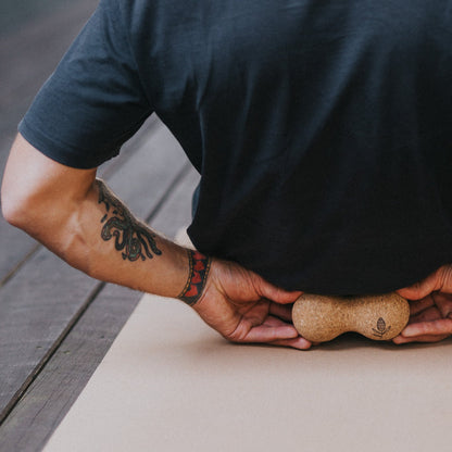 Person using a cork massage roller on a cork yoga mat.