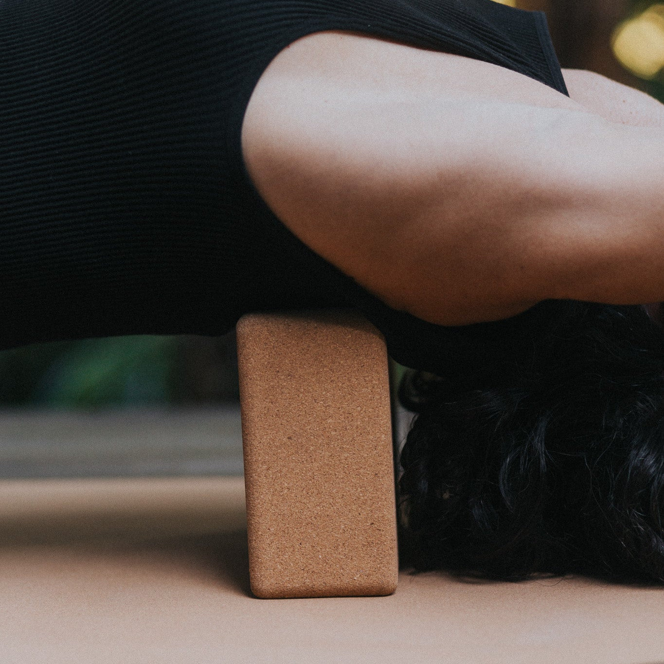 Person using a cork yoga block on a mat outdoors