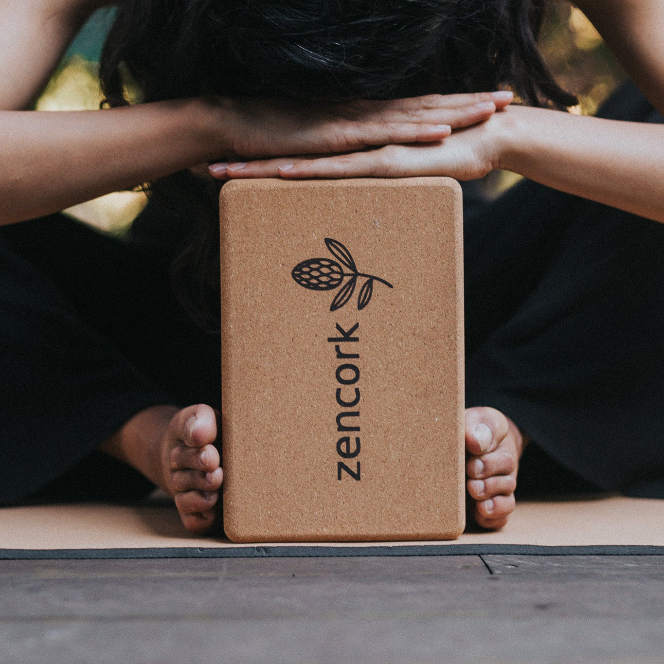 Person using a cork yoga block with 'zencork' branding on a mat.