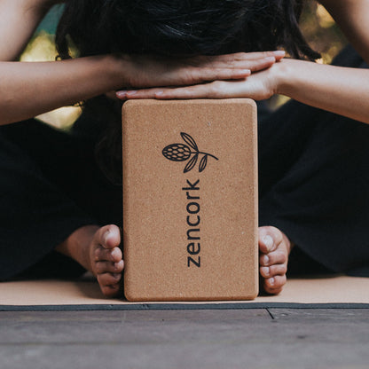 Person using a cork yoga block with 'zencork' branding on a mat.