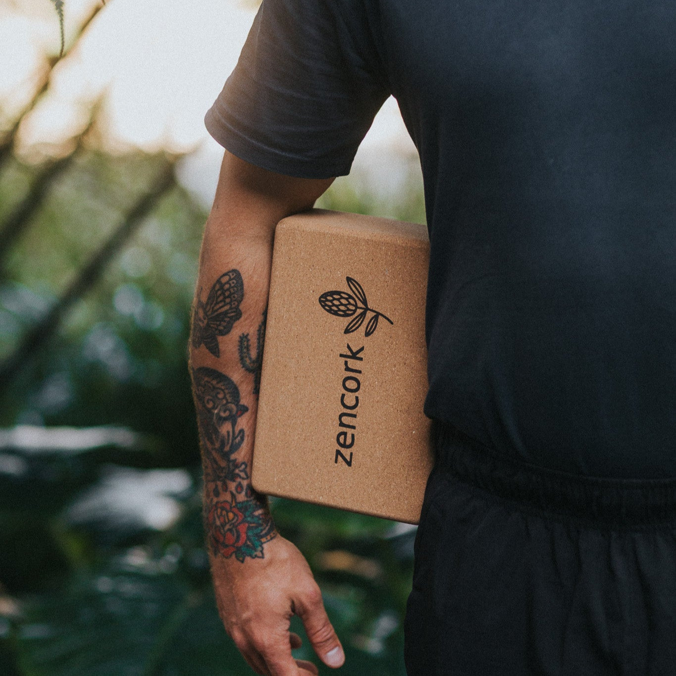 Person holding a cork block with 'zencork' branding against a natural background