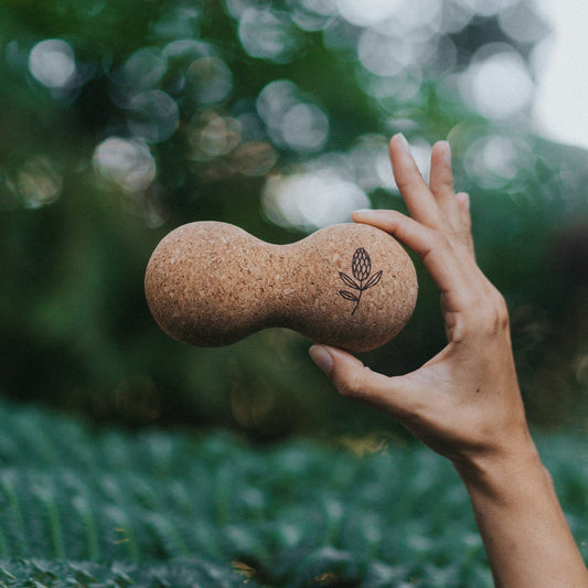 Hand holding a cork ball with a blurred green background