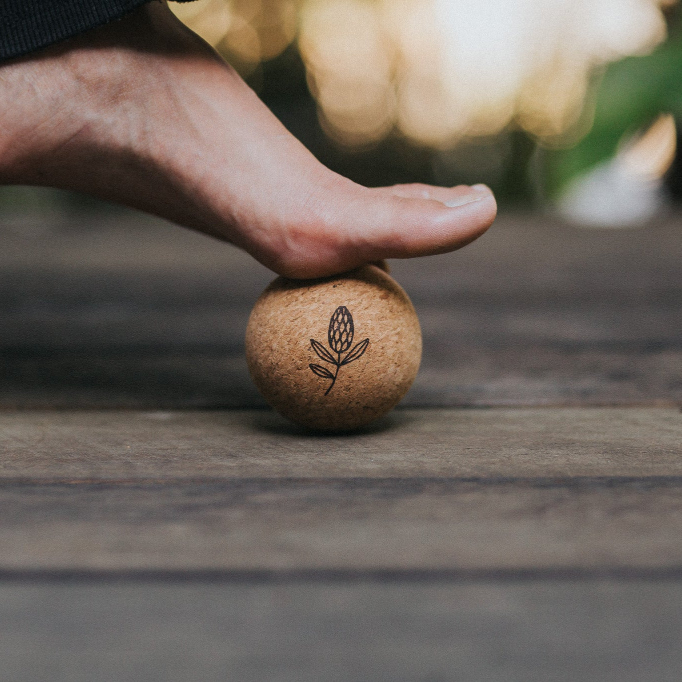 Person stepping onto a cork ball on a wooden surface