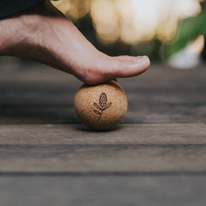Person stepping onto a cork ball on a wooden surface