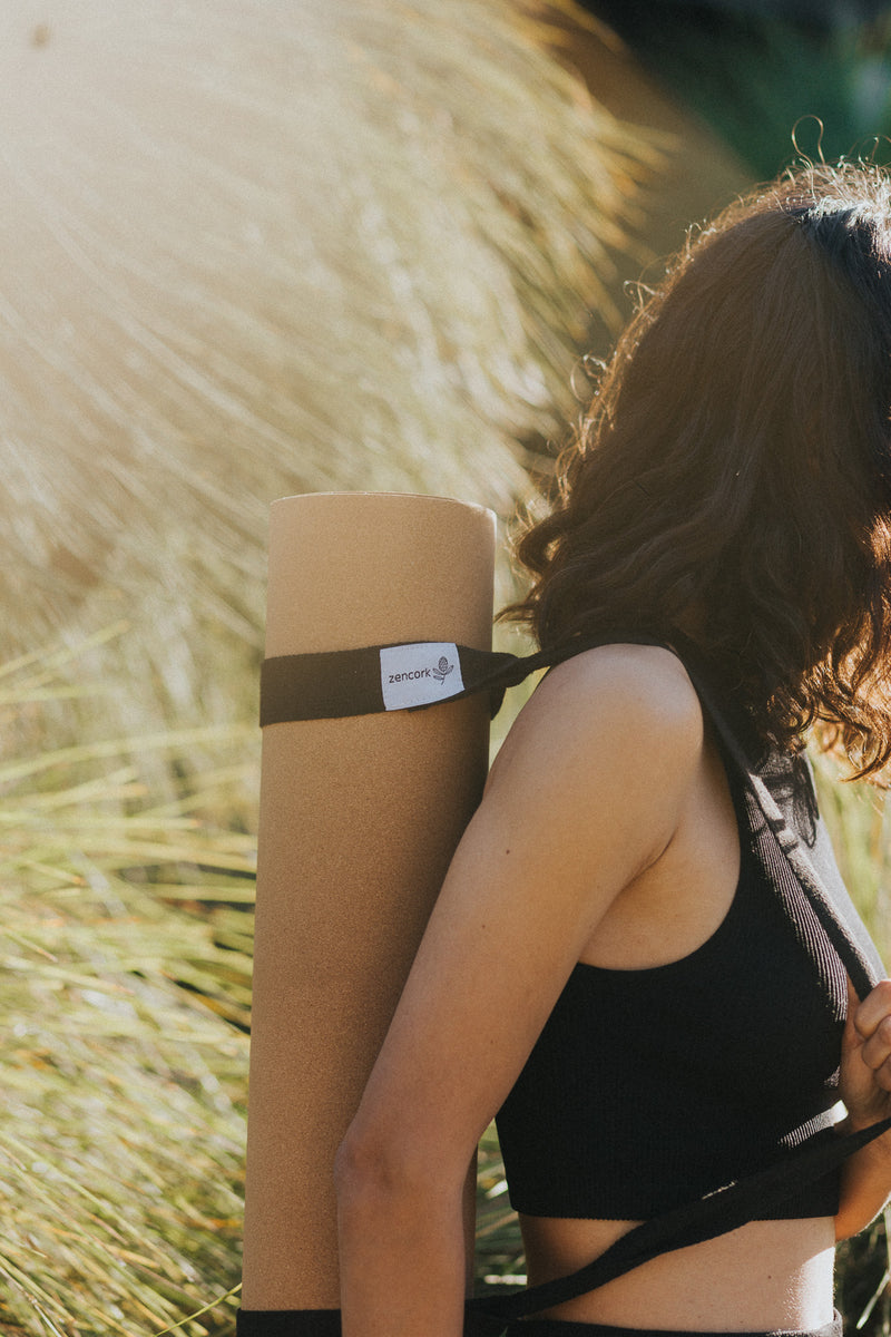 Person holding a yoga mat with a brand logo against a natural background
