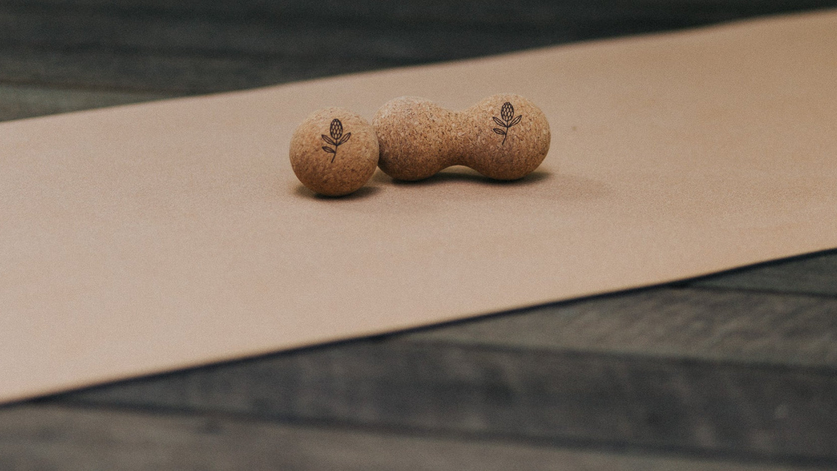 Two cork massage balls on a brown mat with a blurred green background